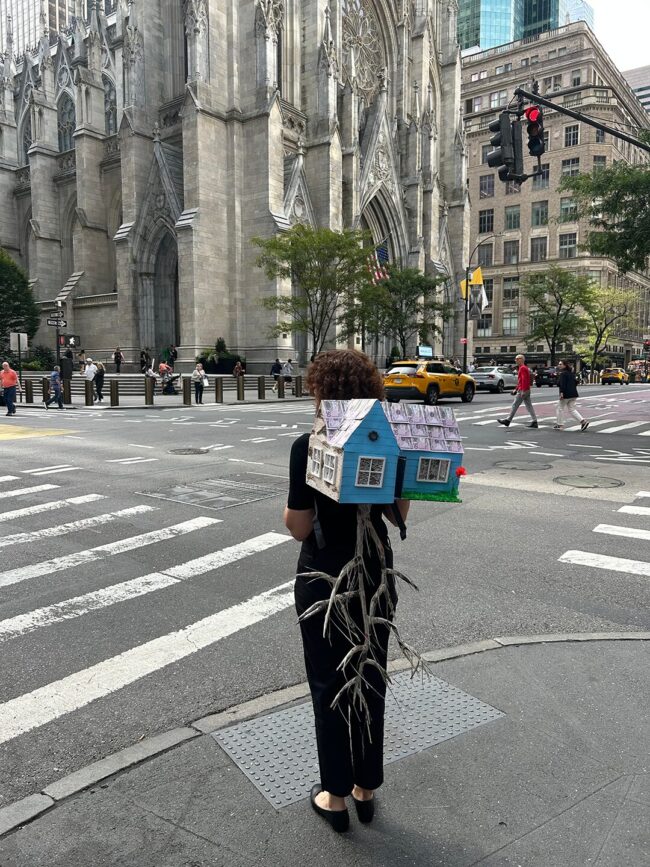 Agnieszka Palka, The Polish Diaspora, Mixed Media including cardboard boxes, newspaper, paper towel, backpack straps, found fabric scraps, collage elements of printed images, prank money, acrylic paint, crepe paper, 41 x 18.5 x 12.25 inches