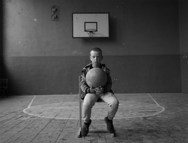 Patrick Patterson, A boy holds a world globe inside his schools gymnasium, Ukraine, Photography